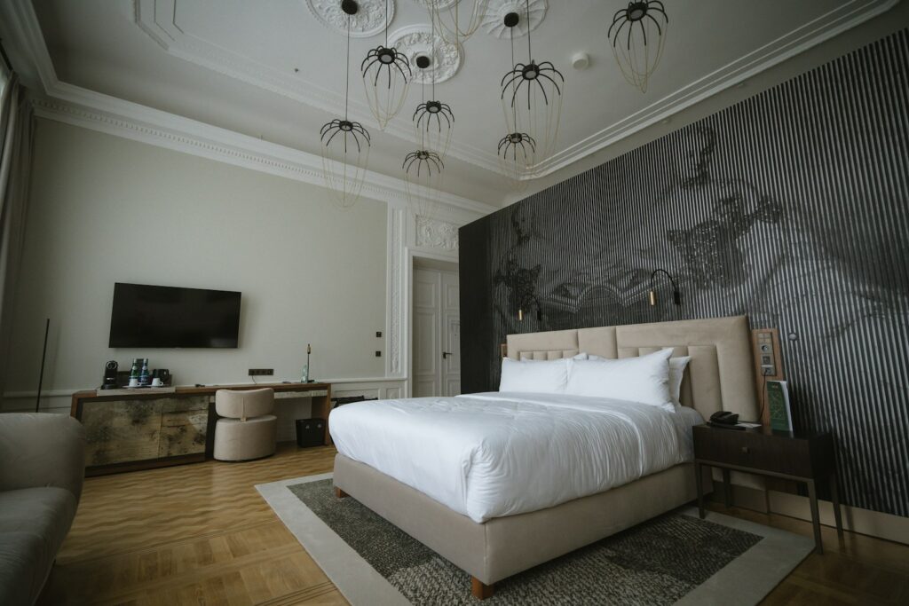 Hotel bedroom with a large made-up bed, wooden floor and pendant lights