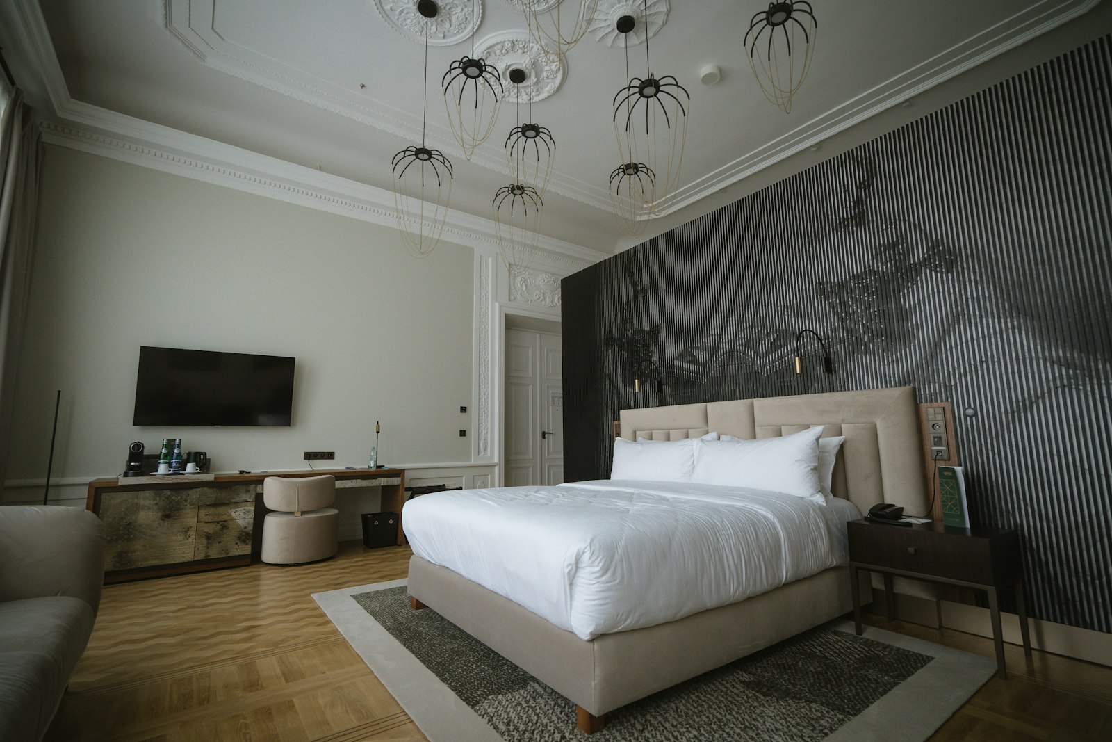 Hotel bedroom with a large made-up bed, wooden floor and pendant lights