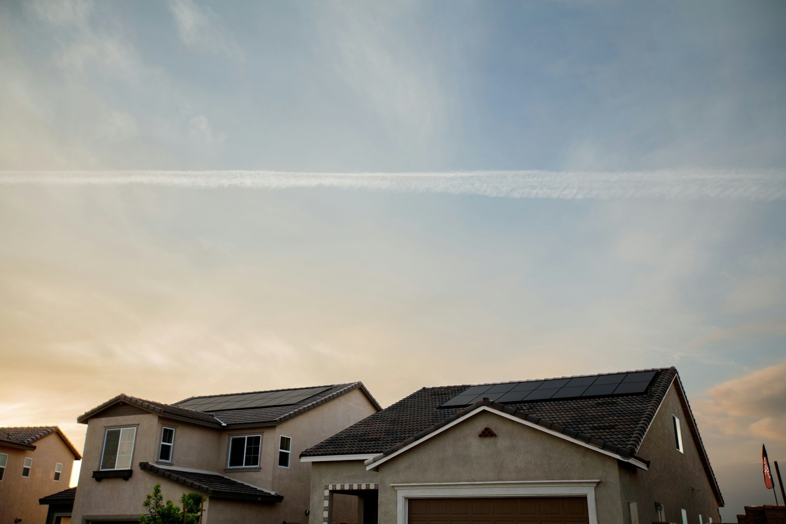 Houses with solar panels on their roofs under an evening sky